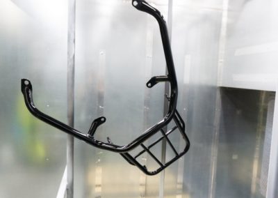 scooter frame hanging in a powder coating booth after cure